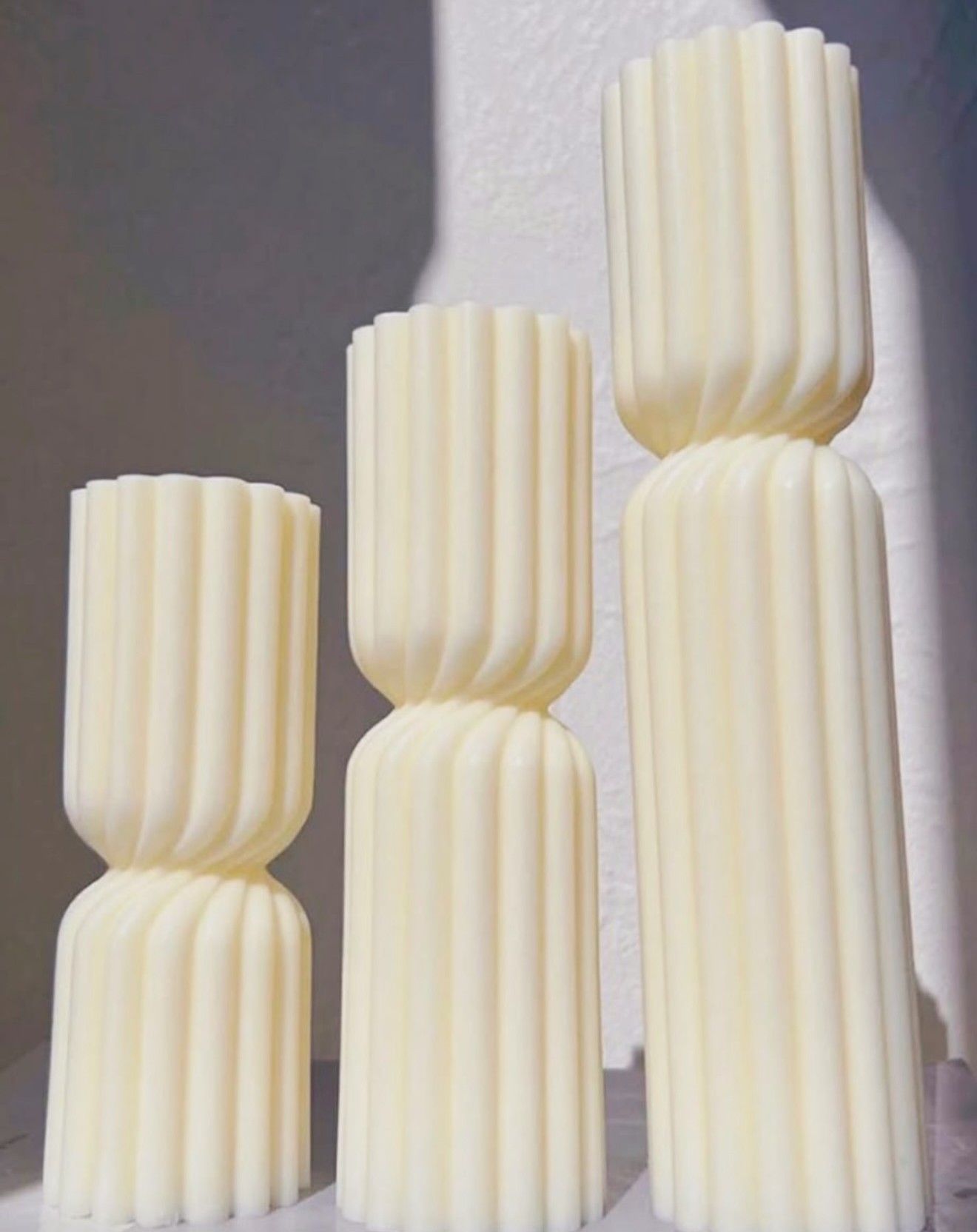 Three tall ribbed cream sculptural candles in a row